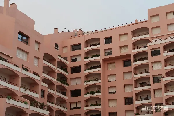 高清摄影 一座大型粉红色建筑，有许多拱形窗户和阳台。
