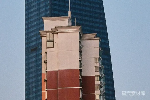 高清摄影 现代玻璃摩天大楼位于一座较旧的住宅建筑后面。