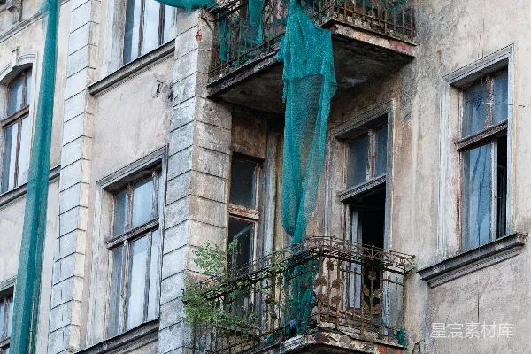 高清摄影 破败的建筑，两个阳台上挂着绿色网纱。