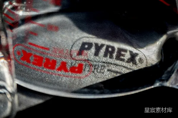 高清摄影 玻璃器皿品牌Pyrex标志特写，背景是皱巴巴的金属。