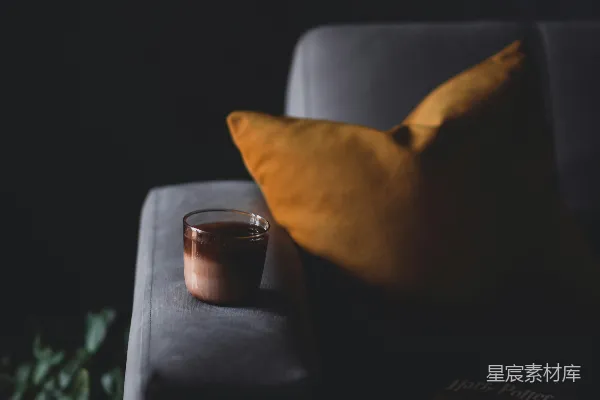 高清摄影 一杯咖啡放在沙发旁边枕头旁边。