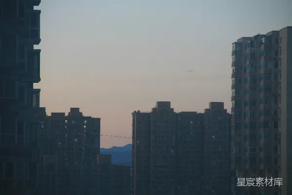 高清摄影 在暮色天空下，高耸的建筑剪影与远处的山脉相映成趣。