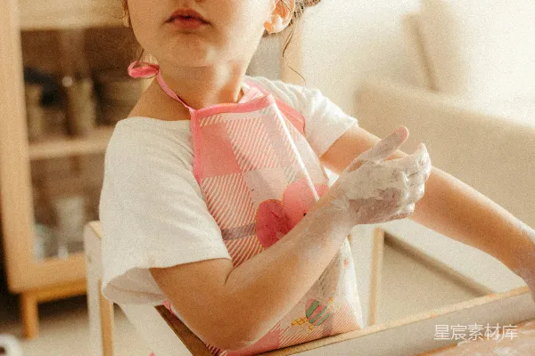 高清摄影 一个满身面粉的小女孩坐在桌子旁边。