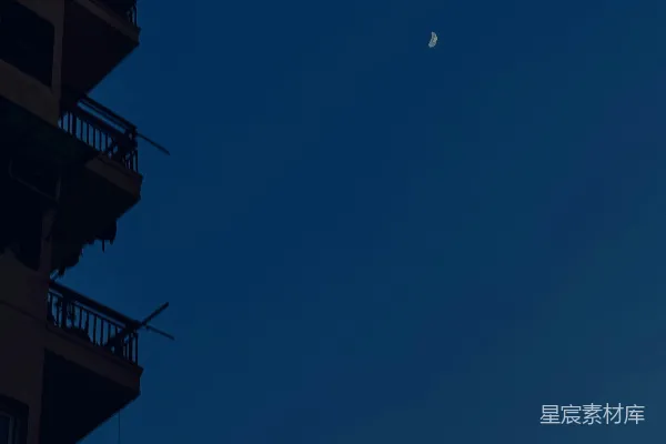 高清摄影 剪影建筑在深蓝色的天空中，月亮呈现出新月形状。