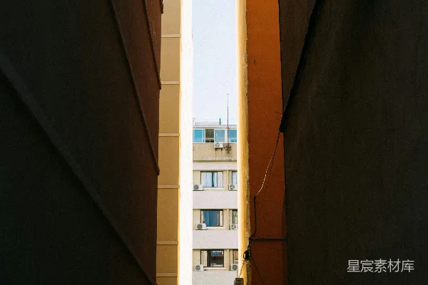 高清摄影 建筑物之间的狭窄巷道，远处可见城市景色。