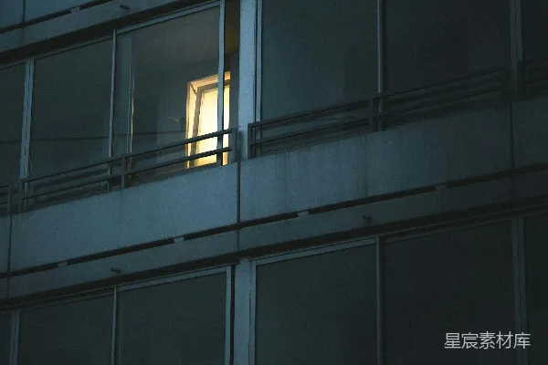高清摄影 一栋黑暗建筑外表上一扇亮着灯的窗户。