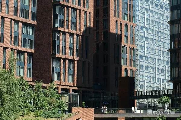 高清摄影 现代砖砌建筑倒映在水中，周围有人和树木。