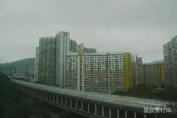 高清摄影 一排高耸的公寓楼沿着山丘排列，紧邻一条铁路。