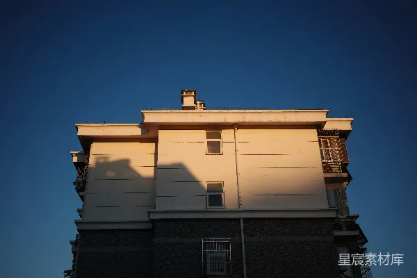 高清摄影 阳光照亮的建筑外墙，背景是清澈的蓝天。