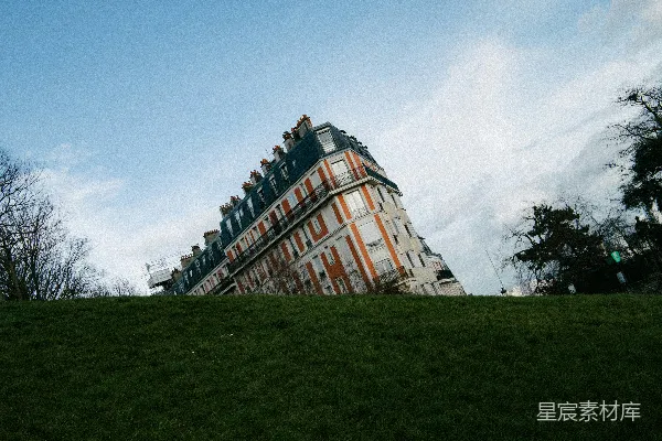 高清摄影 一幢倾斜的建筑坐落在草地上，天空湛蓝。