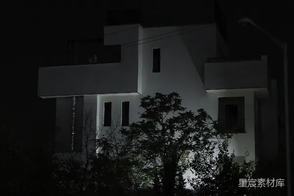 高清摄影 夜晚，一棵树前有一座白色建筑物。