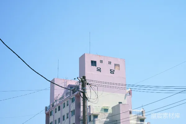 高清摄影 一座紫色的建筑在晴朗的蓝天背景下，下面有韩文。