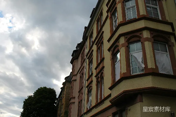高清摄影 一座黄色的建筑，带有突出的窗景，在多云的天空下。
