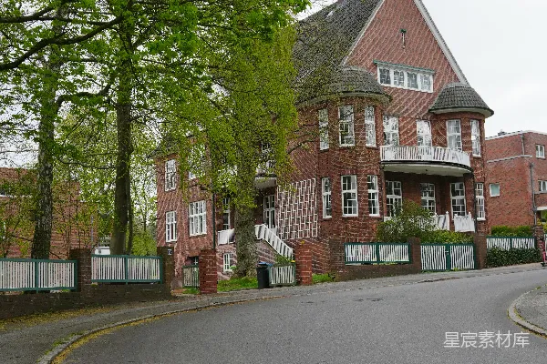 高清摄影 一座大型砖砌建筑，周围有树木和一条弯曲的道路。