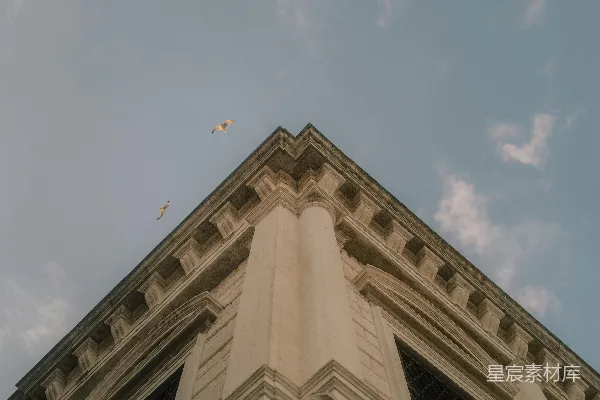 高清摄影 在蓝天下的白天，拍摄到一座米色混凝土建筑的低角度照片。