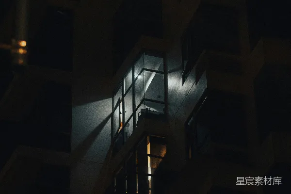 高清摄影 夜晚，一幢黑暗中的建筑里一扇亮着灯的窗户。