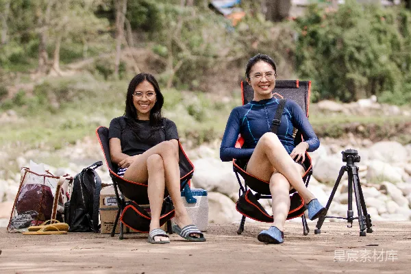 高清摄影 两位女士坐在椅子上，旁边放着一台相机。