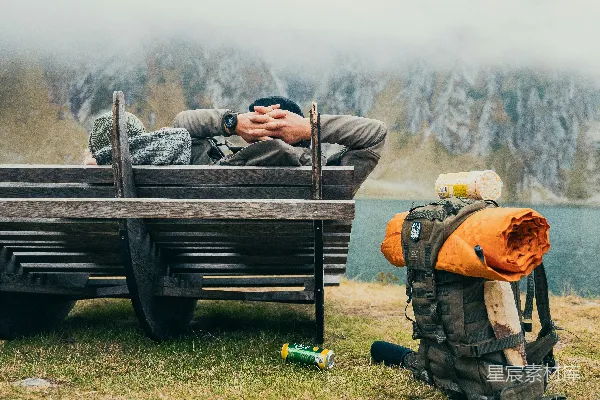 高清摄影 一个男人正躺在长椅上，背着背包睡觉。