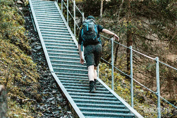 高清摄影 穿黑色夹克和蓝色牛仔裤的男人正在灰色金属桥上行走。