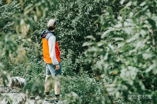 高清摄影 一个穿着橙白相间衬衫的男人在白天走在土路上。