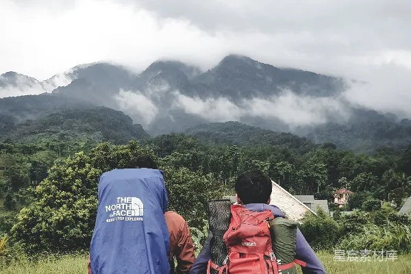 高清摄影 穿着红色夹克和黑色背包的男人站在白天的绿草地上。