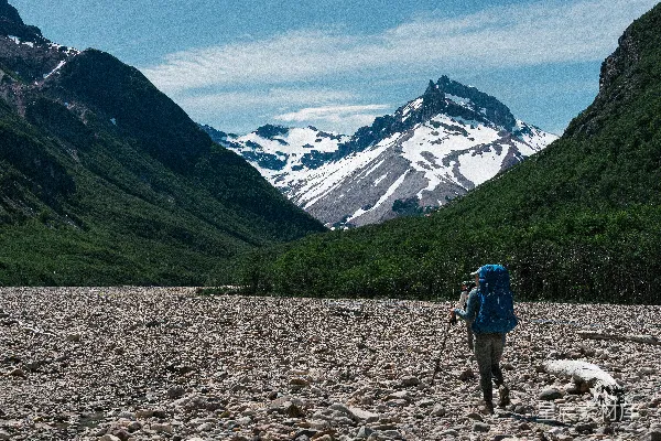 高清摄影 背着背包的人在岩石地带行走，背景是山脉。