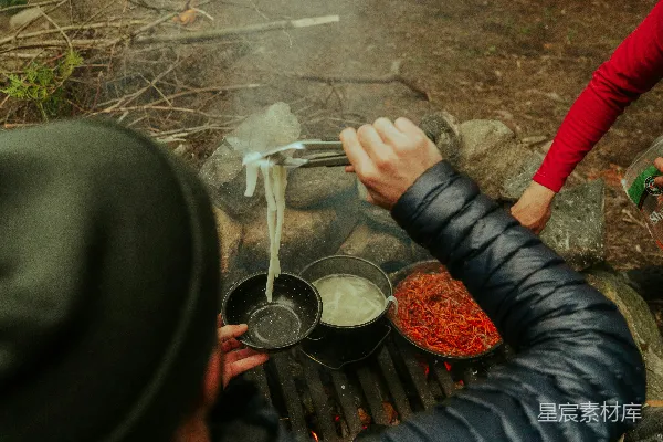 高清摄影 一个男人和一个女人在篝火旁做饭。