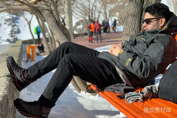 高清摄影 戴墨镜的男人穿着冬装，在雪地上休息。