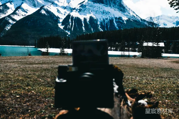 高清摄影 相机拍摄在积雪的山脉和湖泊背景下的树桩。