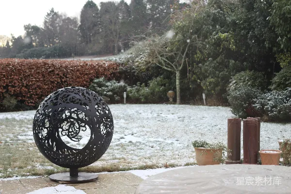 高清摄影 装饰性球形火坑在雪地花园环境中。