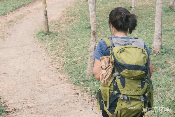 高清摄影 背着背包的女人在泥泞的小路上行走。