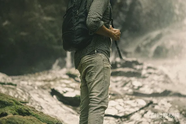 高清摄影 一个背着背包的男人站在岩石上，瀑布前。
