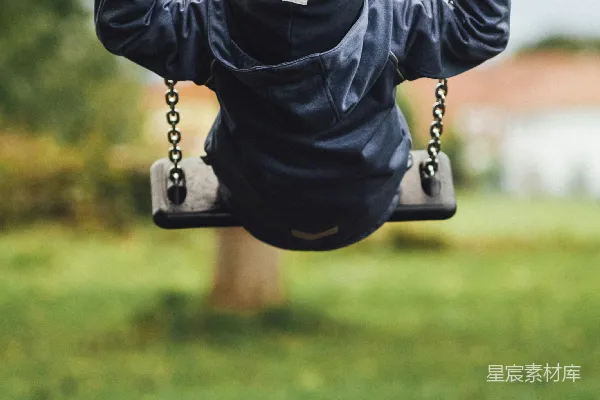 高清摄影 穿着灰色长袖衬衫的孩子坐在白天的秋千上。