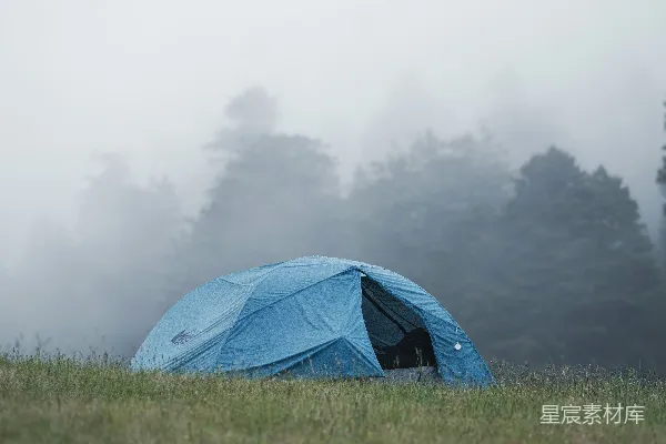 高清摄影 在雾蒙蒙的森林空地上，有一顶蓝色的野营帐篷。