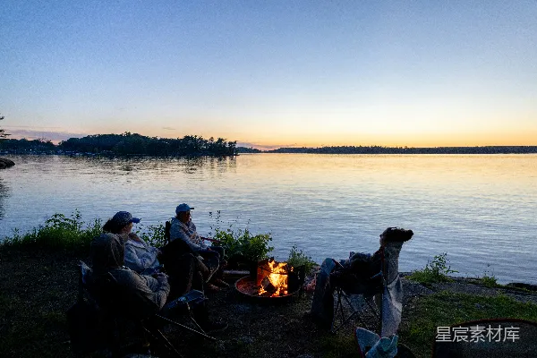 高清摄影 人们围坐在湖边篝火旁，夕阳西下。