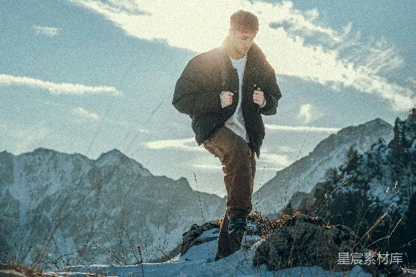 高清摄影 一个男子在晴朗的天空下攀登积雪覆盖的山峰。