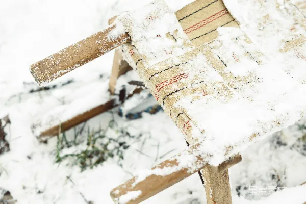 高清摄影 一把木椅坐在积雪覆盖的地面上。