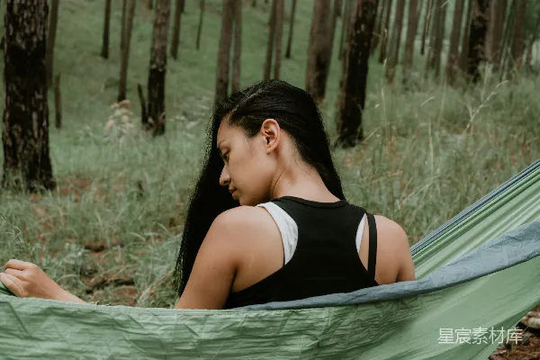 高清摄影 穿黑色上衣的女人坐在绿色吊床上。