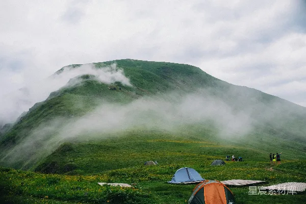高清摄影 在薄雾缭绕、绿意盎然的山脚下露营。