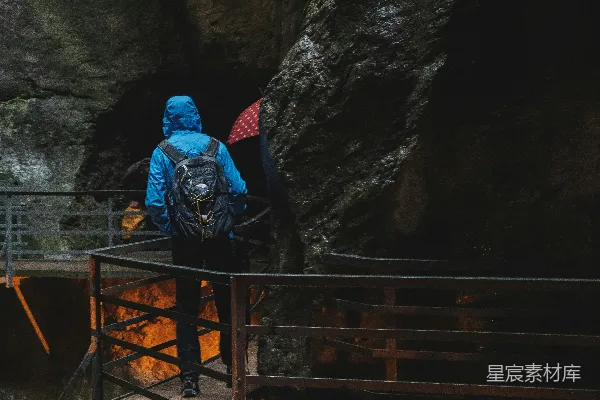 高清摄影 穿蓝色连帽夹克的人站在洞穴附近的桥上。