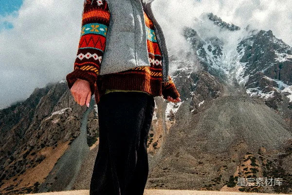 高清摄影 穿着五颜六色毛衣的女子站在壮丽的雪山前。