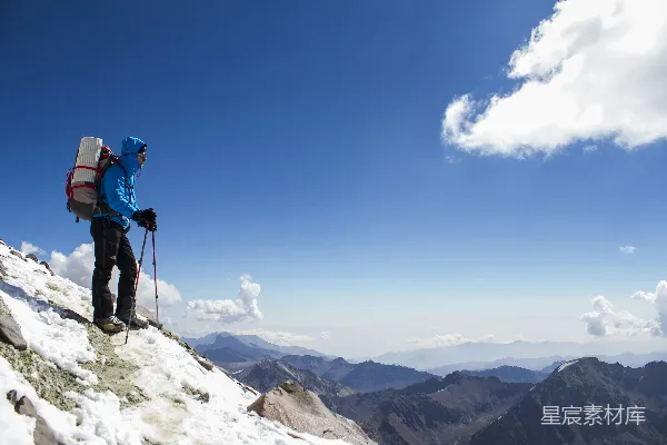 高清摄影 背着背包的男人正在一座积雪的山上徒步上行