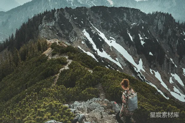 高清摄影 白天，一位穿着白色长袖衬衫的女人坐在岩石上，背景是山脉。