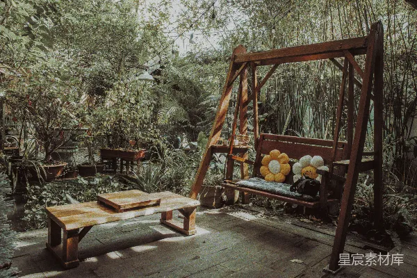 高清摄影 在郁郁葱葱的花园中，有木制秋千和餐桌。