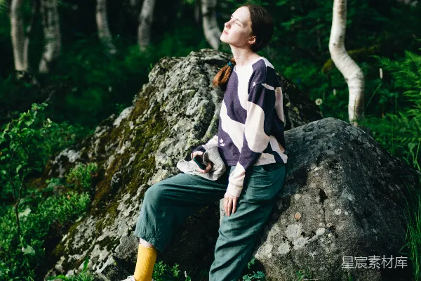 高清摄影 一个女人坐在树林中的岩石上