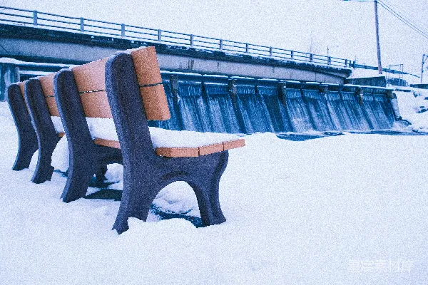 高清摄影 冬日覆盖着积雪的公园长椅，旁边有一座桥。