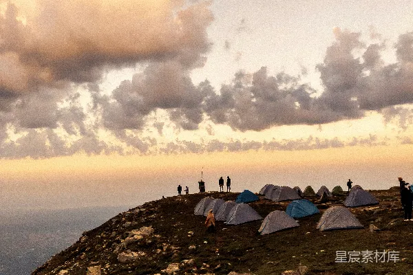 高清摄影 帐篷和人们在山坡上露营，夕阳西下。