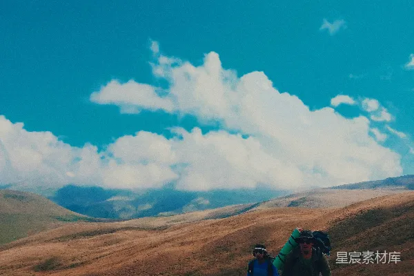 高清摄影 人们在白天的蓝天白云下，褐色的山上徒步旅行。