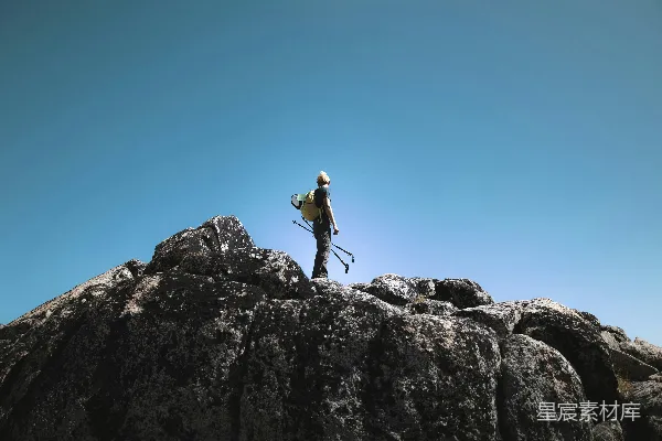 高清摄影 徒步者站在岩石山顶上，背景是清澈的蓝天。