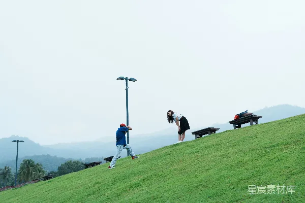 高清摄影 在草地上的人们，背后是连绵的山脉。